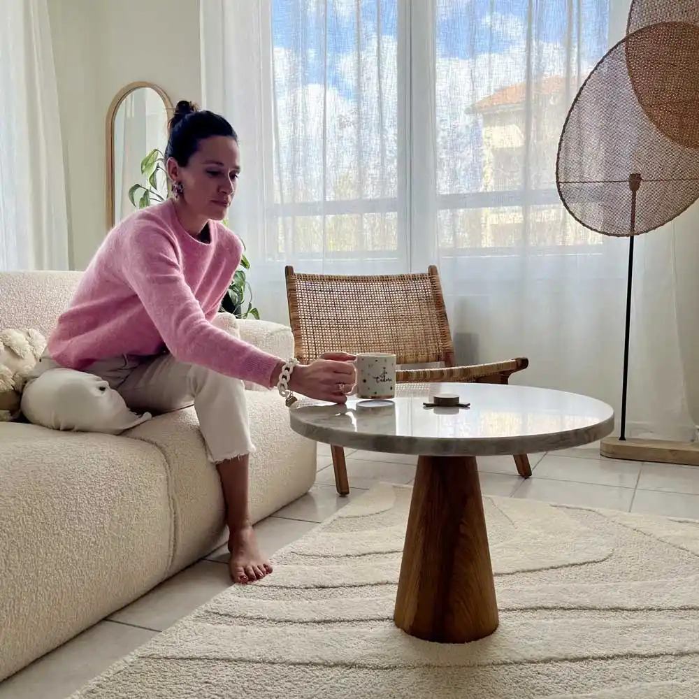 Table basse en marbre marque C'est bien fait dans un salon intemporel avec une femme qui se prélasse. consommation responsable